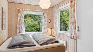 A bedroom with a bed, two windows with curtains, a wooden ceiling, and a door. - 4 Star Holiday Home in Hemmet (Hemmet)
