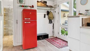 A compact kitchen with a red refrigerator, white cabinets, and a window providing a view of the outdoors. - 4 Star Holiday Home in Hemmet (Hemmet)
