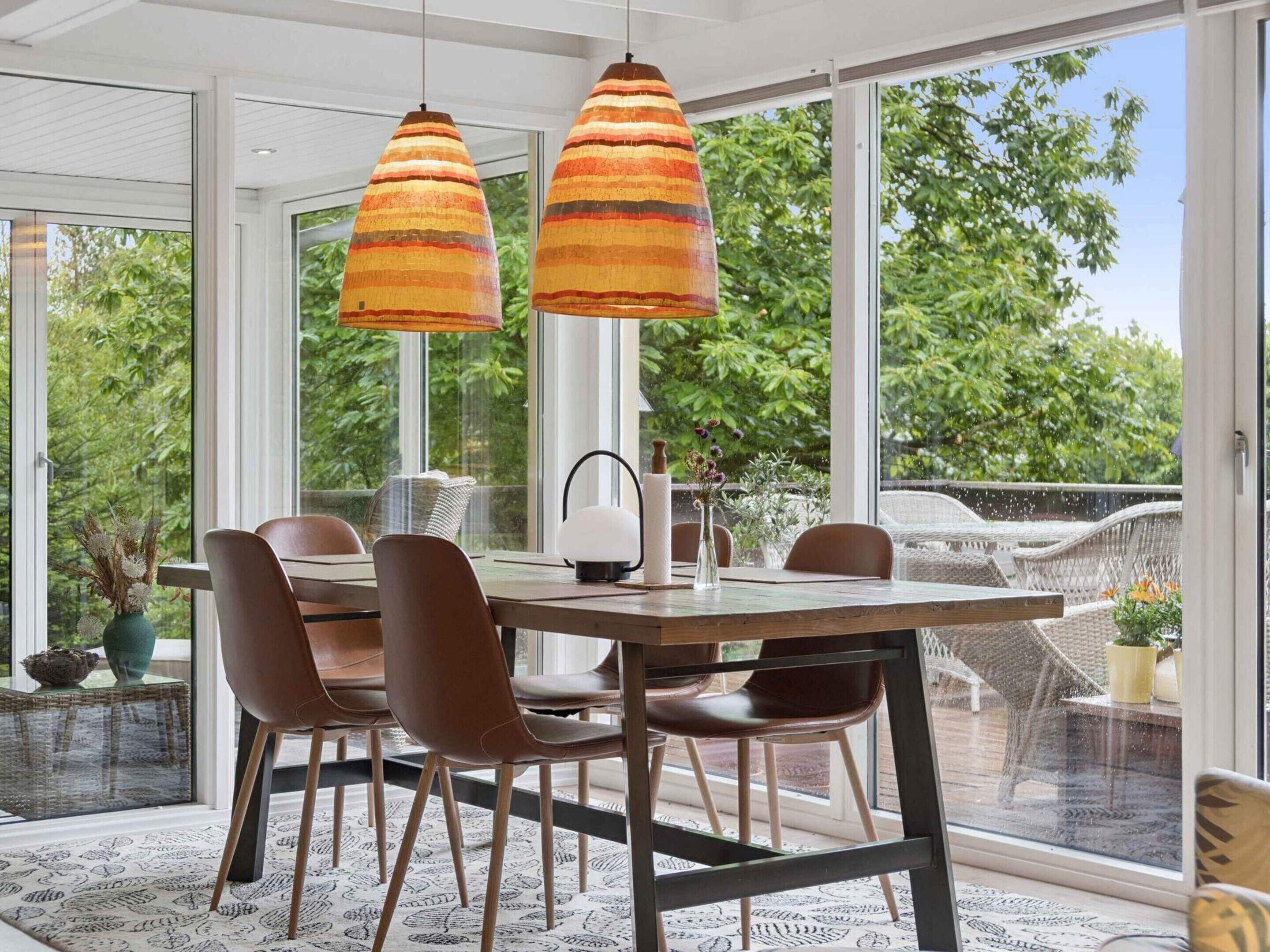 A modern dining area with a large table, chairs, and pendant lights.