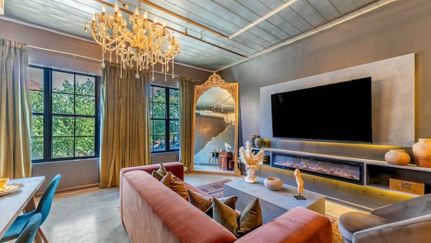 Een moderne woonkamer met een grote televisie, een open haard en een kroonluchter.