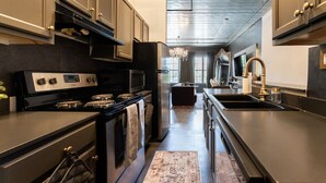 Een moderne keuken met roestvrijstalen apparatuur, een centraal eiland en uitzicht op de woonkamer.