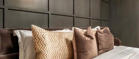 A bed with a dark headboard and multiple pillows in various patterns and textures.