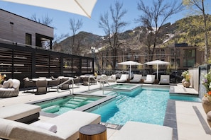 A pool area with lounge chairs, umbrellas, and a view of mountains. - White Elephant Aspen (Aspen)