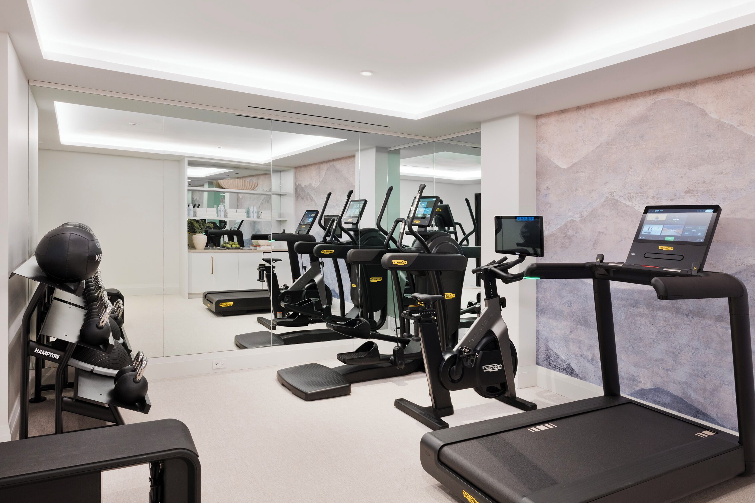 A modern gym with treadmills, elliptical machines, and a rowing machine.