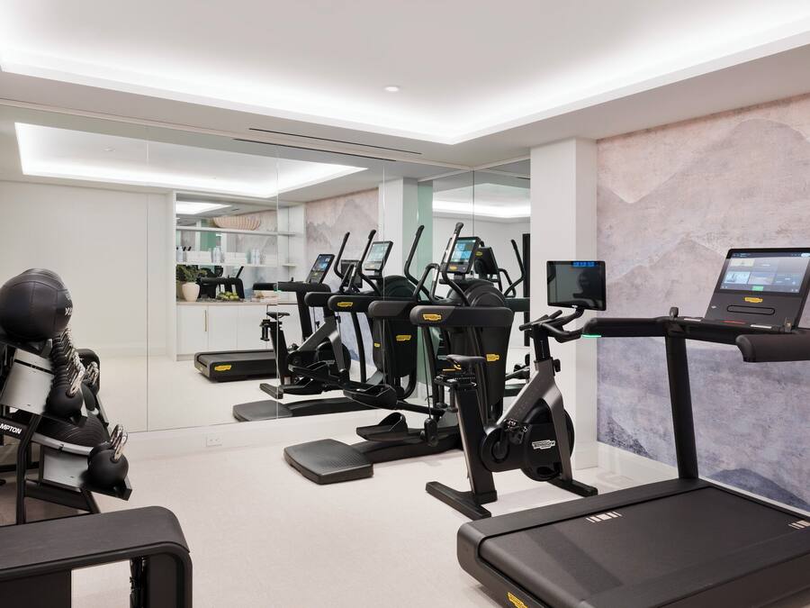 A modern gym with treadmills, elliptical machines, and a rowing machine.