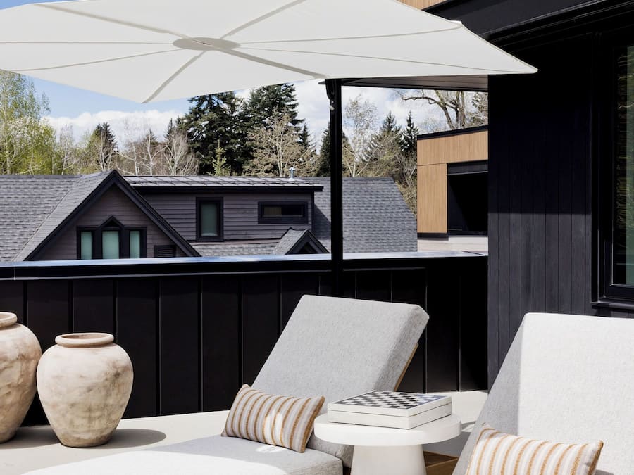 An outdoor seating area with two cushioned chairs, a small table, and a large umbrella.