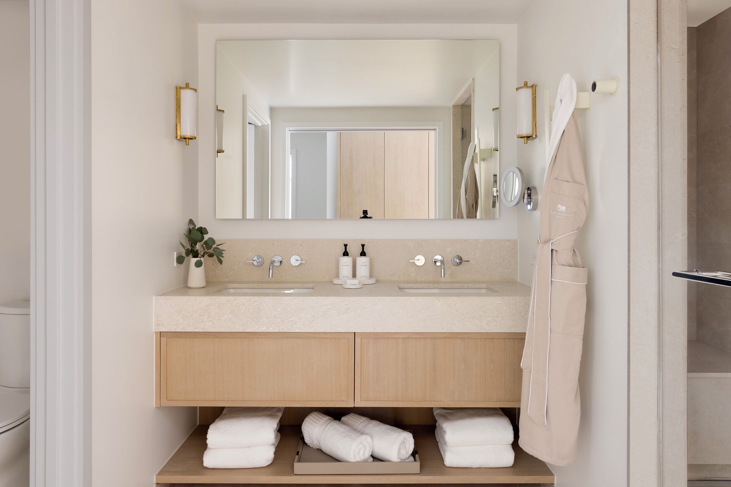 A modern bathroom with two sinks, a large mirror, and a towel rack.
