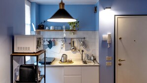 Une cuisine compacte équipée d’un four à micro-ondes, d’une bouilloire et de divers ustensiles disposés sur le plan de travail.