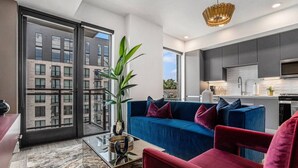 A modern living room with a blue sofa, red armchair, and a glass coffee table. - A Cozy Luxurious Stay Buckhead Atlanta (Atlanta)