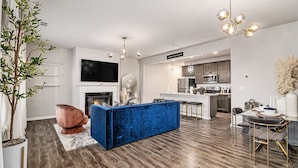 A modern living room with a blue sofa, a fireplace, and a kitchen in the background.
