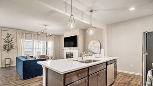 A modern kitchen with a large island, built-in appliances, and pendant lighting.