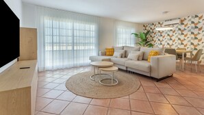 Un salon moderne avec un canapé, une table basse et un téléviseur posé sur un meuble.