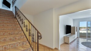 Un escalier orné de carreaux décoratifs, un téléviseur à écran plat et une vue à travers une porte vitrée.