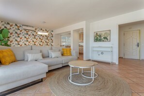A modern living room with a sofa, a round coffee table, and a patterned wall.