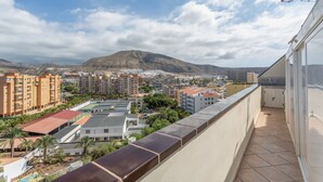 Un balcon offrant une vue sur le paysage urbain, avec des bâtiments et une montagne en toile de fond.