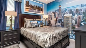A bedroom with a cityscape mural, a bed with patterned bedding, two bedside tables with lamps, and a dresser.