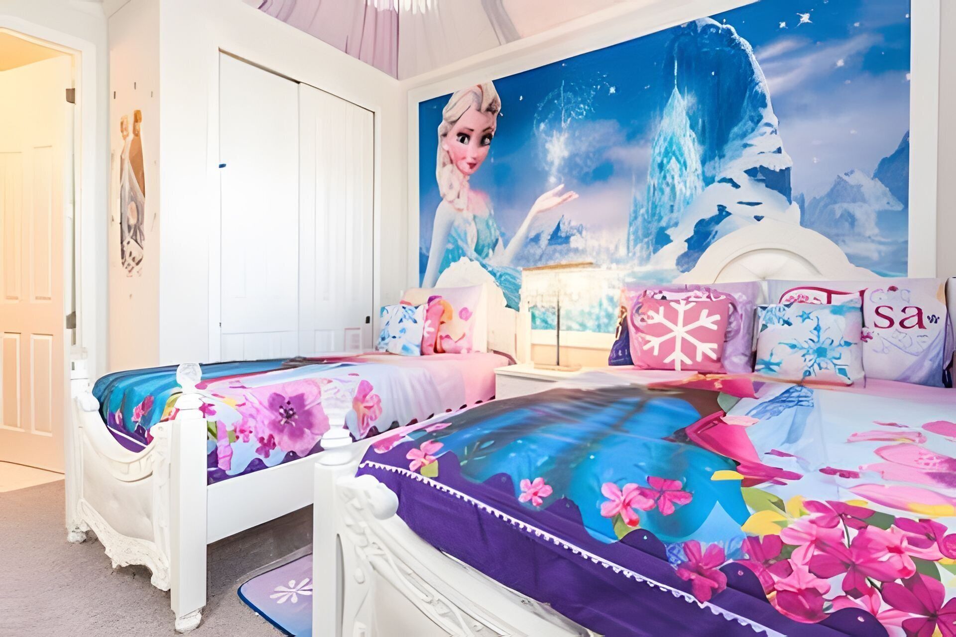 Un dormitorio con dos camas, cada una con ropa de cama floral, un gran mural de un paisaje invernal y una puerta blanca.