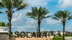 A sign with 'SOLARA' prominently displayed, surrounded by palm trees and modern buildings in the background.