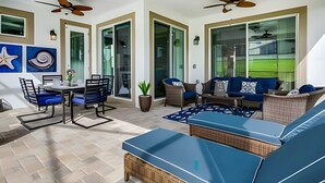 A spacious patio area with a dining table, chairs, a sofa, and a ceiling fan.