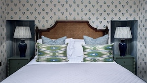 A neatly made bed with patterned pillows, a wooden headboard, and two bedside tables with lamps.