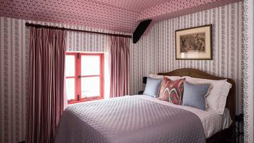 Een slaapkamer met een bed, gordijnen, een raam en een lijst met een afbeelding aan de muur.
