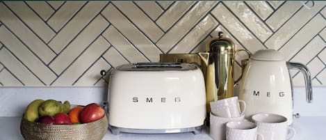 Una encimera de cocina con un tostador, una cafetera y un frutero.