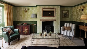 A traditional living room with a fireplace, green walls, and classic furniture.