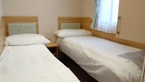 A room with two single beds, each with a wooden headboard and a nightstand.