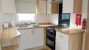 A compact kitchen with white cabinets, a black stove, and a window.