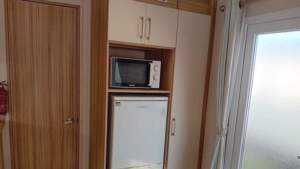 A compact kitchen with a white refrigerator, a microwave, and wooden cabinets.