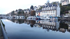 Un rivage paisible où sont amarrés des bateaux, qui se reflètent dans les bâtiments et la rue.