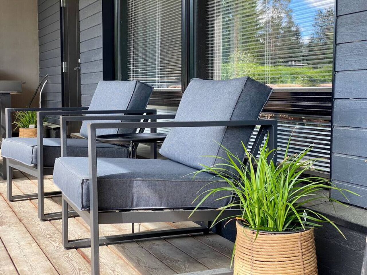 Un espacio al aire libre moderno con dos sillones grises y una planta en maceta.
