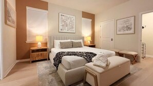 A modern bedroom with a large bed, bedside tables, a bench, and artwork on the walls. - Luxury Oasis 8BR Villa - Windsor Cay Resort (Clermont)
