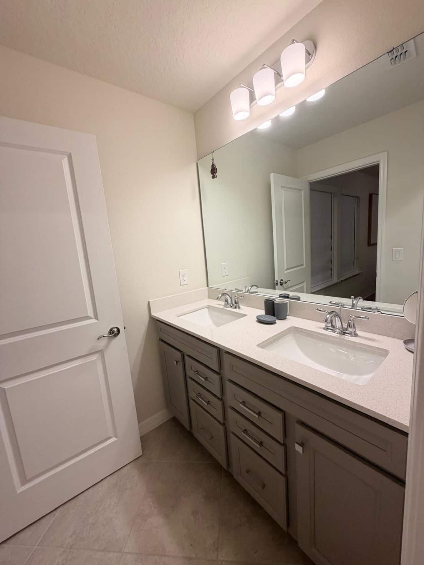 A bathroom with two sinks, a large mirror, and a door.