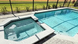 A rectangular swimming pool with a hot tub adjacent to it, surrounded by a paved deck and a metal fence. - Luxury Oasis 8BR Villa - Windsor Cay Resort (Clermont)