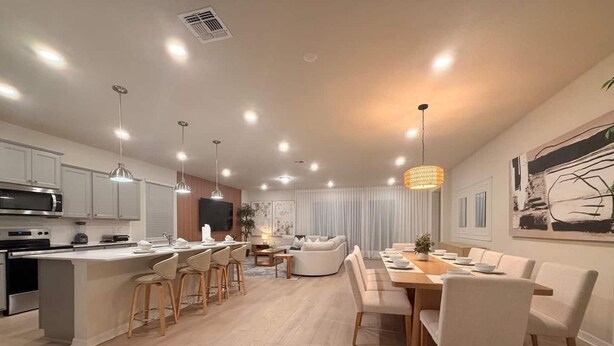A modern kitchen with a central island, bar stools, and pendant lighting. - Luxury Oasis 8BR Villa - Windsor Cay Resort (Clermont)