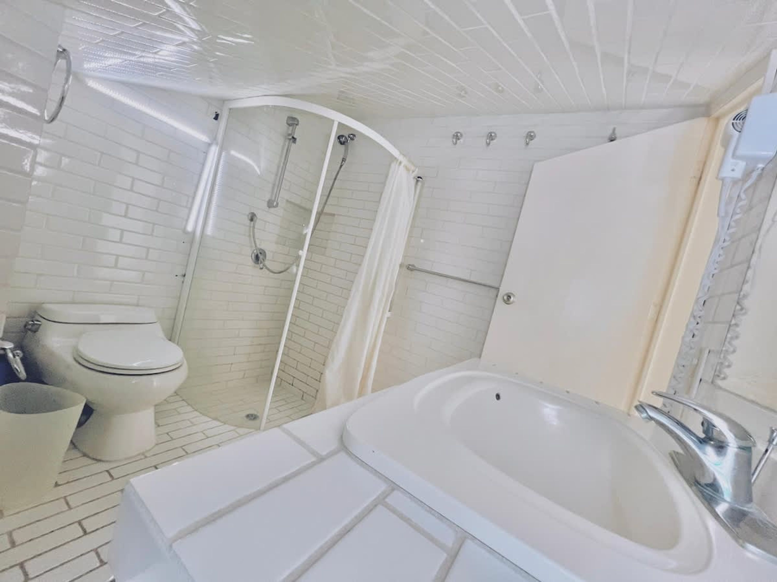 A bathroom with a white bathtub, a toilet, and a glass-enclosed shower area.