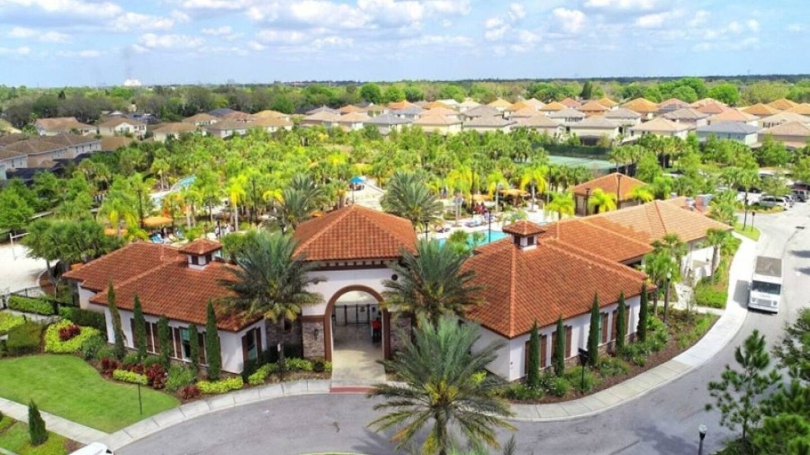 Zona residencial con casas de tejas rojas, rodeada de exuberante vegetación y palmeras.