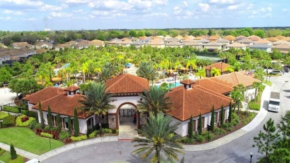 A residential area with houses featuring red-tiled roofs, surrounded by lush greenery and palm trees.