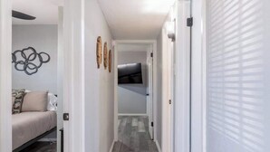 Un passadís amb un llit, un ventilador de sostre i un televisor fixat a la paret.