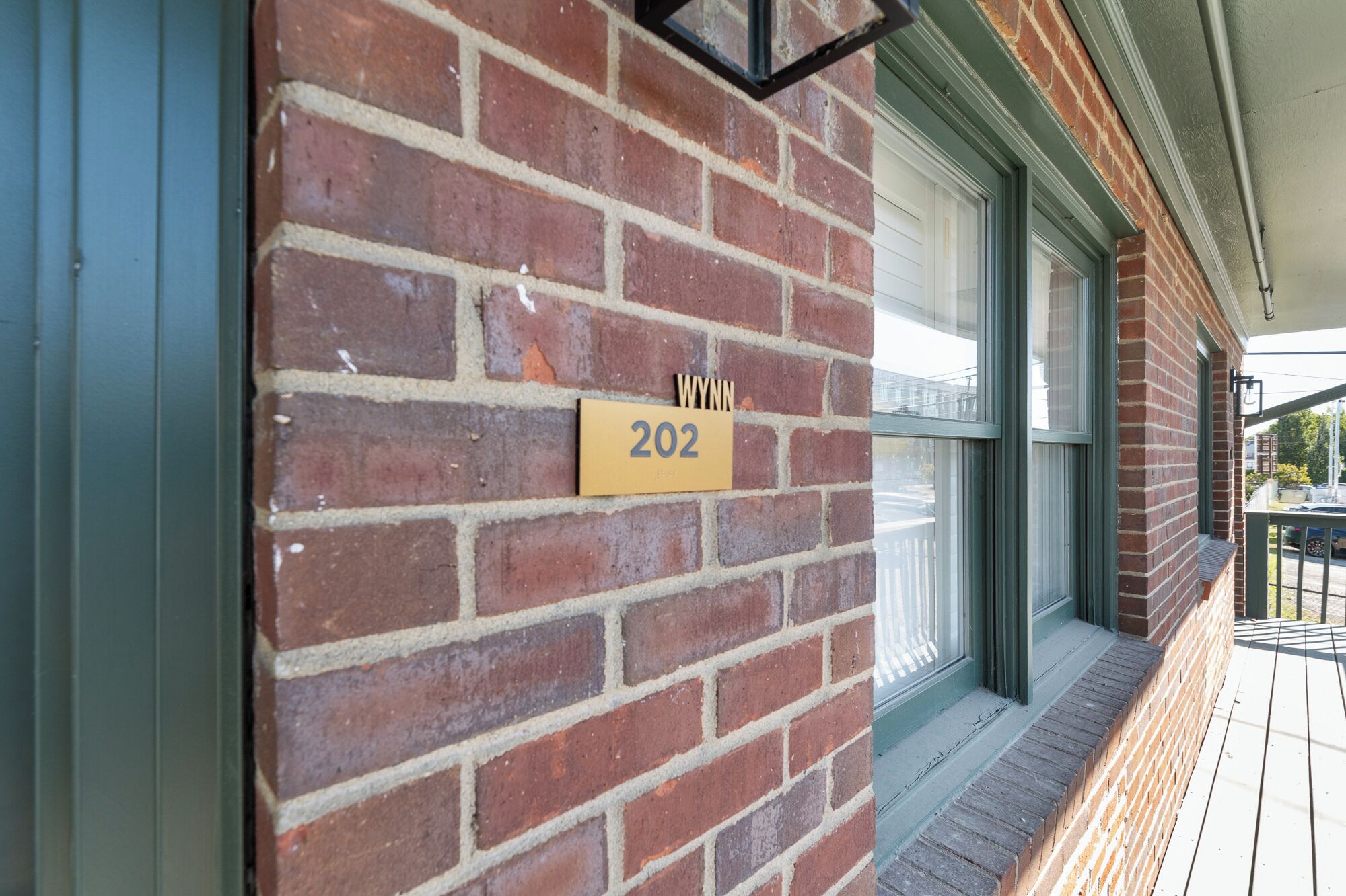 A brick wall with a yellow house number sign displaying '202'.