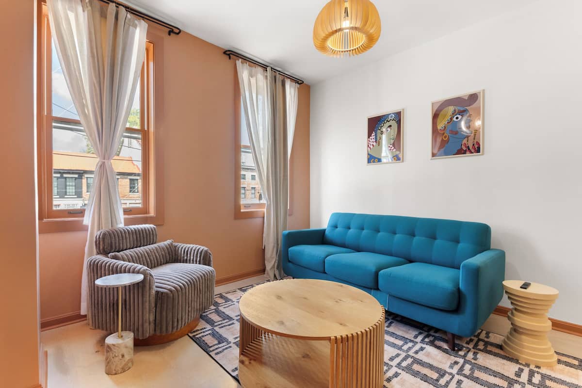 Ein modernes Wohnzimmer mit einem blauen Sofa, einem gestreiften Sessel und einem runden Holztisch.