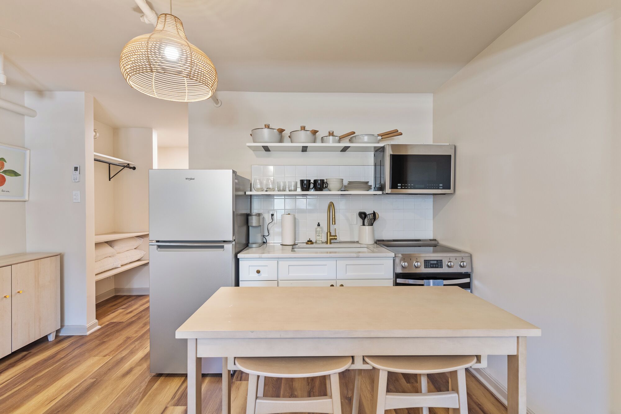 A compact kitchen with a central island, white cabinetry, a built-in microwave, and a hanging light fixture.