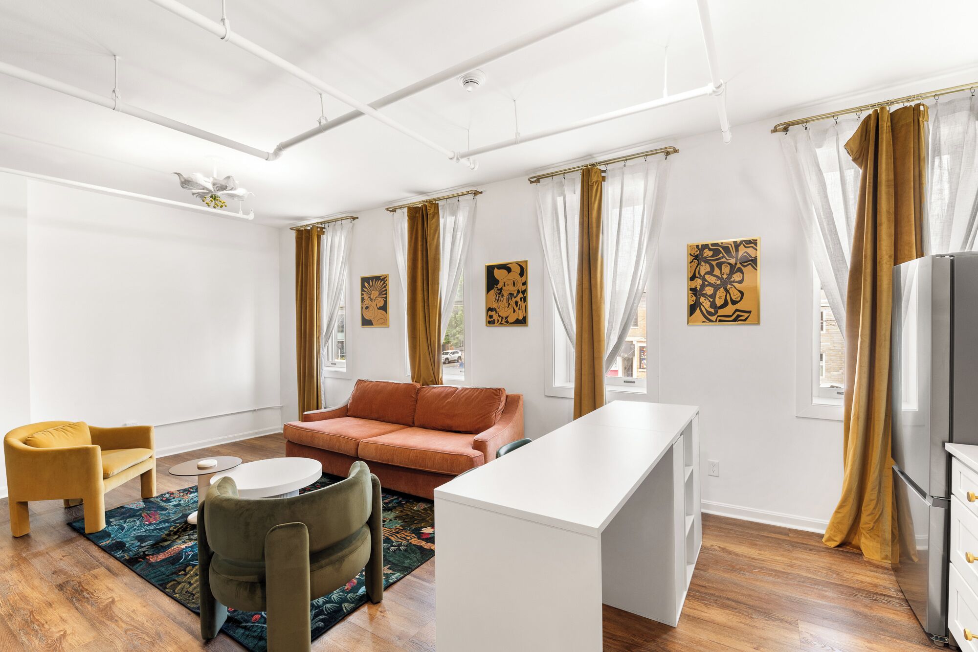 Een moderne woonkamer met een bank, een klein tafeltje, een televisie en kunstwerken aan de muur.