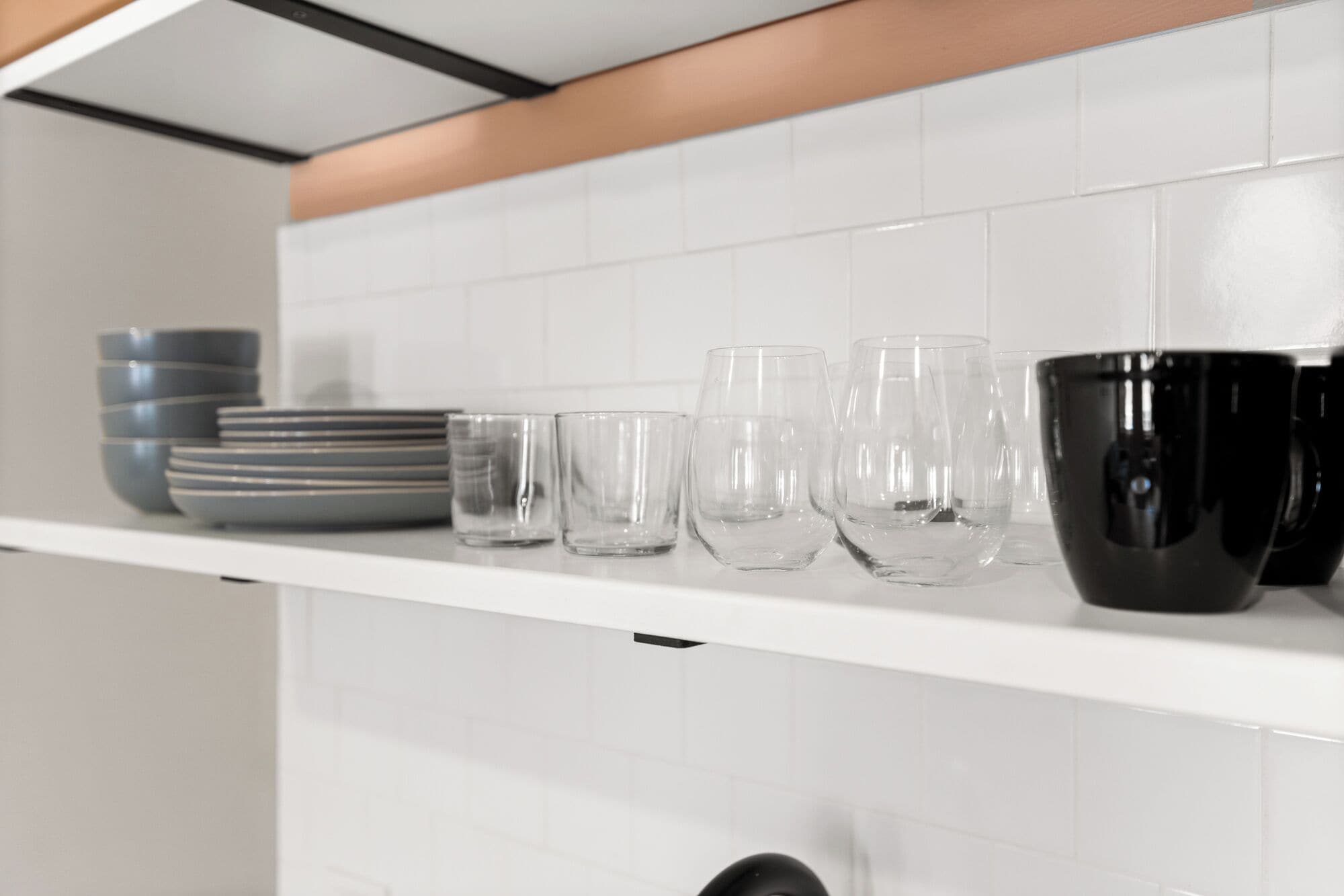 Une étagère de cuisine contenant divers objets en verre et des bols.