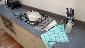 A kitchen with a stove, pots, a toaster, a kettle, and a knife block. - Altillo Puerto Claro (Valparaíso)