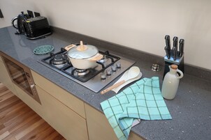 Une cuisine équipée d’une cuisinière, de casseroles, d’un grille-pain, d’une bouilloire et d’un bloc à couteaux.