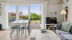 Ein geräumiges Wohnzimmer mit Essbereich, einer Couch, einem Fernseher und einem Balkon mit Meerblick.
