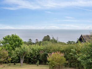 Un paisaje costero con una construcción rústica, abundante vegetación y vista al mar.