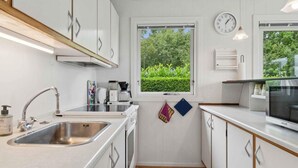 Eine moderne Küche mit weißen Schränken, einer Edelstahl-Spüle, einer Kaffeemaschine und einer Mikrowelle.